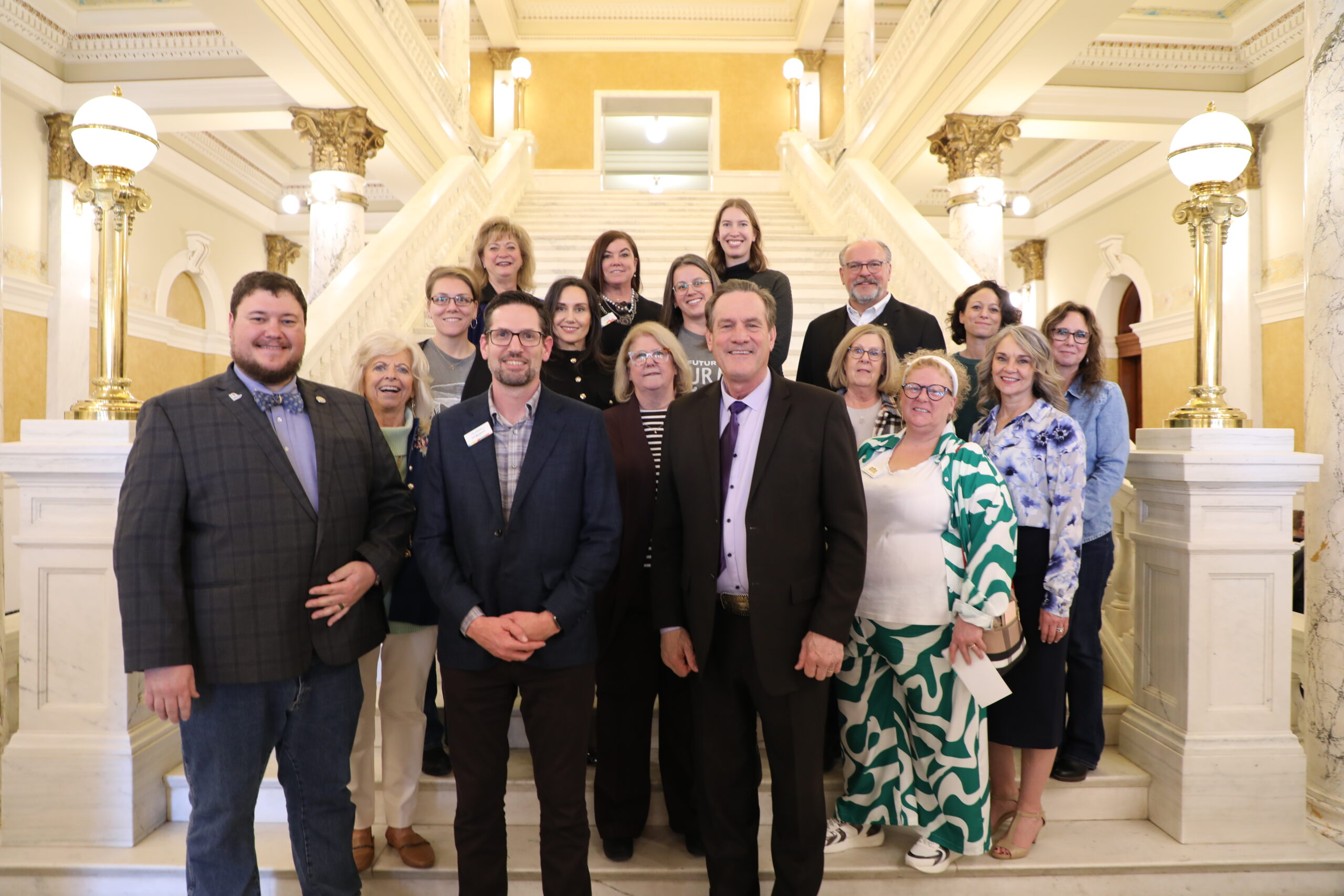 A group of colleagues standing together indoors, smiling in a professional setting.